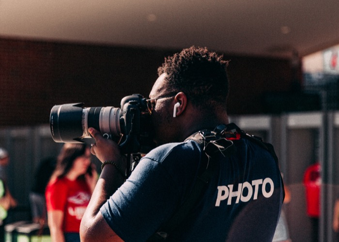 A man at an event taking a photograph with a professional camera.